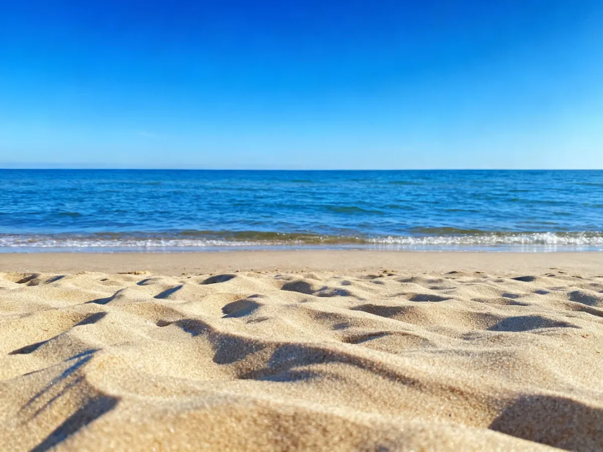 Słoneczna plaża w Chłopach ze złotym piaskiem i spokojnym Bałtykiem w pełnym słońcu.